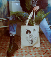 Close-up of the model with the “Male Tears” Natural Tote Bag, showcasing its comfortable fit and bold design in a real-world setting